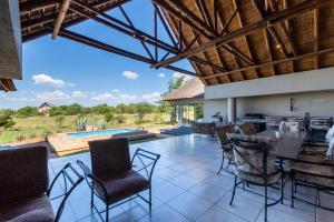 a patio with a table and chairs and a pool at Zebula - HT1 - 5 Bedroom Holiday Home in Mabula