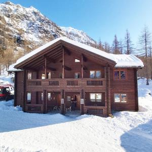 una cabaña de madera en la nieve con una montaña en Chalet Rosa dei Monti, en Valprato Soana