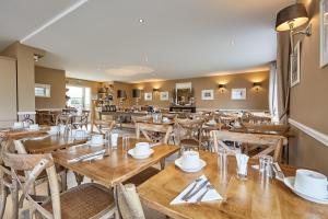 a dining room with wooden tables and chairs at Les Villas d'Arromanches, Teritoria in Arromanches-les-Bains