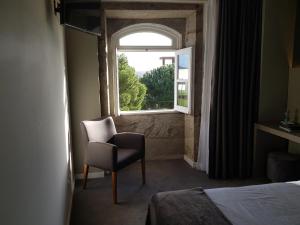 um quarto com uma cadeira e uma janela em Hotel Margarida Da Praça em Viana do Castelo
