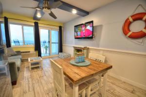 een woonkamer met een tafel en een tv aan de muur bij Emerald Villa in Panama City Beach
