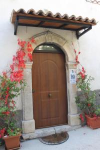 una puerta de madera en un edificio con flores rojas en Medieval Village of Pacentro, en Pacentro