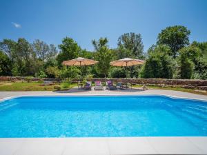 una piscina con due ombrelloni e sedie di Holiday Home Mila by Interhome a Kras