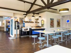 - une cuisine avec des tables et des tabourets dans une pièce dans l'établissement Hôtel Ibis Budget Nantes Ouest Atlantis Couëron, à Couëron