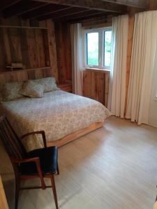 - une chambre avec un lit, une chaise et une fenêtre dans l'établissement Au Vieux Foyer, à Saint-Pierre-de-l'Île-d'Orléans