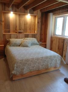 una camera con un letto in una stanza con pareti in legno di Au Vieux Foyer a St-Pierre-de-l'Île-d'Orléans