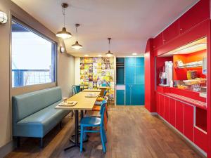 ein Restaurant mit einem Tisch, Stühlen und roten Schränken in der Unterkunft hotelF1 Les Ulis Courtaboeuf in Les Ulis