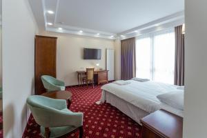 a hotel room with a bed and chairs and a table at Ambassador Hotel in Chişinău +57 photos
