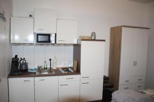 uma cozinha com armários brancos, um lavatório e um micro-ondas em Ferienwohnung Möwennest I em Emden