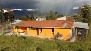 una casa amarilla con techo rojo en una colina en HOSPEDAJE CARIGAN, en Loja