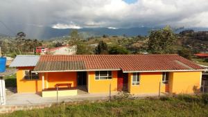 una casa amarilla con techo rojo en una colina en HOSPEDAJE CARIGAN, en Loja