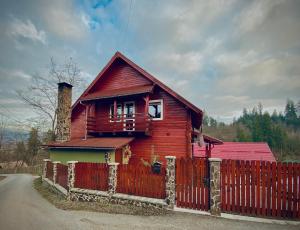 una casa de madera con una valla delante en Cabana Scruba, en Topliţa