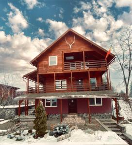 a large log house in the snow with snow at Cabana Scruba in Topliţa