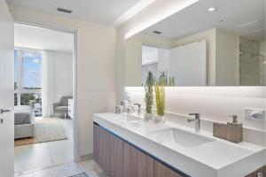 La salle de bains blanche est pourvue d'un lavabo et d'un miroir. dans l'établissement 914 Tiffany House condo, à Fort Lauderdale