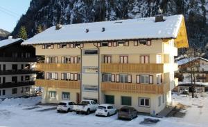 a building with cars parked in front of it in the snow at Appartamenti Col Rodella by AMA Val di Fassa in Campitello di Fassa