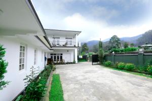 a white house with a balcony and a driveway at Sapu's Mountain breeze Nuwara Eliya in Nuwara Eliya