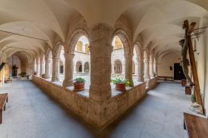 a hallway with arches and potted plants in a building at San Francesco Heritage Hotel in Alghero