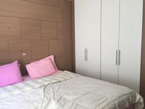 a bedroom with a bed with pink pillows at APARTAMENTO ACONCHEGANTE in Uberlândia