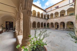an empty courtyard in a building with a column at San Francesco Heritage Hotel in Alghero