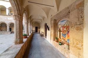 a hallway in a building with paintings on the walls at San Francesco Heritage Hotel in Alghero