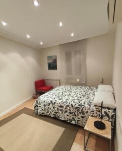 um quarto com uma cama e uma cadeira vermelha em Casa Duquesa em Logroño