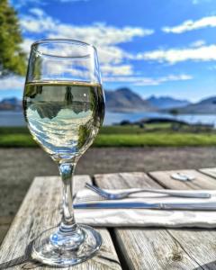 
a glass of wine sitting on top of a wooden table at Raasay House Hotel in Raasay
