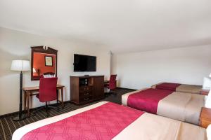 a hotel room with two beds and a desk and a tv at Rodeway Inn in Cedar Rapids