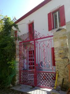 a red gate on a white house with red windows at Epavli Sofia' s two Apartments in Horto, 30m from the sea in Chorto