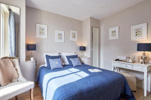 a bedroom with a blue bed and a chair at Les Villas d'Arromanches, Teritoria in Arromanches-les-Bains