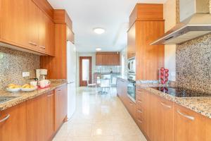 エンプリアブラバにあるApart-rent Villa Pani 0109の木製キャビネットと御影石のカウンタートップが備わる広いキッチン