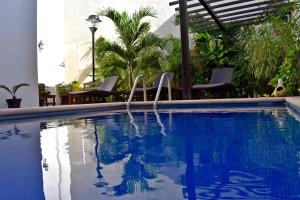 a swimming pool with two chairs next to a building at Hotel Casa Rosario in Valladolid
