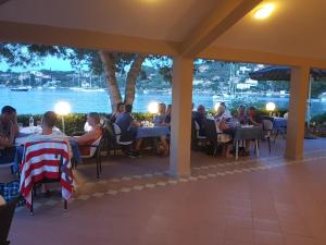un grupo de personas sentadas en mesas en un restaurante en Hotel Paradise Punta, en Nečujam