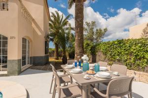 a patio with a table and chairs and palm trees at VILLA CARYANA II in Cala en Blanes