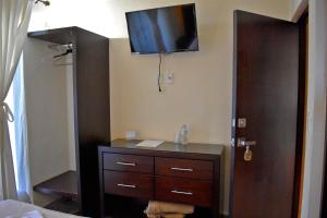 a room with a dresser with a flat screen tv on the wall at Hotel Casa Rosario in Valladolid