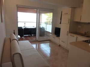 a kitchen with a couch and a large sliding glass door at Apartments Ori in Tkon