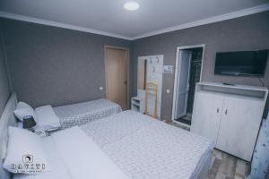 a small bedroom with two beds and a television at Hotel Tskhumi in Kutaisi