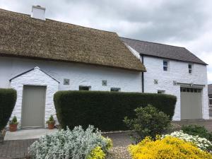 a white house with a grass roof at Connells House Thatched Cottage in Duleek