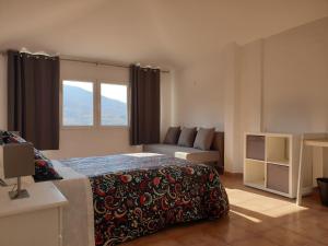 a bedroom with a bed and a couch and a window at Portales de Pizarro in Béjar
