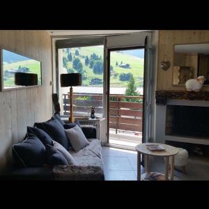 a living room with a couch and a fireplace at Le doux nid des ARAVIS in La Clusaz