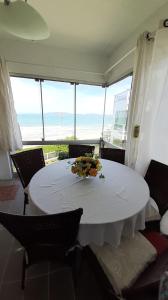 Itapema-Meia Praia- 3 quartos - Frente Mar! في ايتابيما: غرفة طعام مع طاولة بيضاء وإطلالة على المحيط +51 صورة