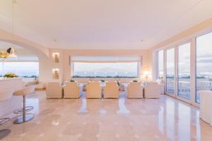 a living room with a table and chairs and large windows at Grand Hotel Aminta in Sorrento