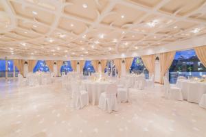 a ballroom with white tables and chairs and large windows at Grand Hotel Aminta in Sorrento