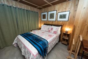 - une chambre avec un lit dans une pièce dotée de murs en bois dans l'établissement Auberge Le Four à Pain, à Petite-Rivière-Saint-François