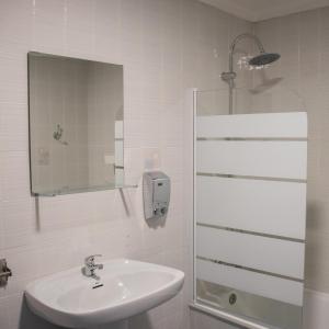 a white bathroom with a sink and a shower at Hostal Caminito del Rey in Alora