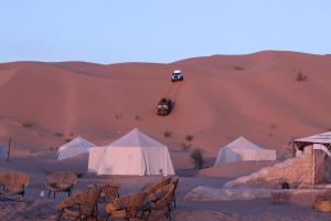 Un désert avec des tentes et une voiture dans le sable dans l'établissement Camp Mars, à Douz