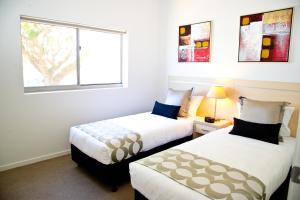 dwa łóżka w pokoju z oknem w obiekcie Jacana Apartments w mieście Townsville