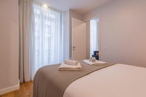 ein weißes Schlafzimmer mit einem Bett mit Handtüchern darauf in der Unterkunft Upscale & Modern 2BDR Apartment in Lissabon