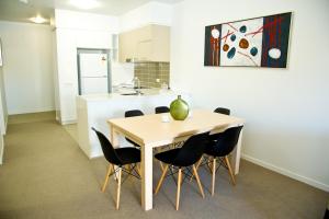 cocina con mesa de madera y sillas negras en Jacana Apartments en Townsville