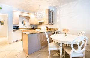 a kitchen with a white table and white chairs at Beach Living at Island Pine Villas (BLV) in George Town