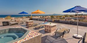 a patio with a swimming pool and tables and umbrellas at THE BONGOS - Socially Conscious Rooms, Part of the room rate goes to charity in Maleme